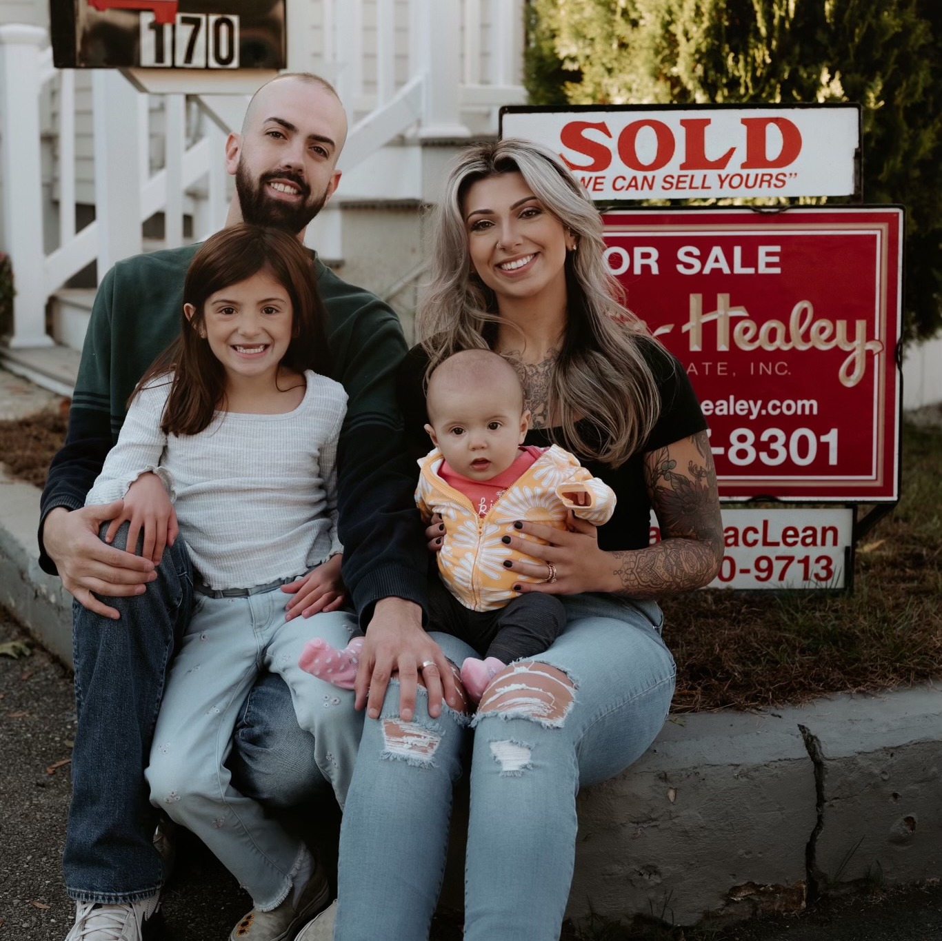 Dylan MacLean with family in front of a Foster-Healey SOLD sign
